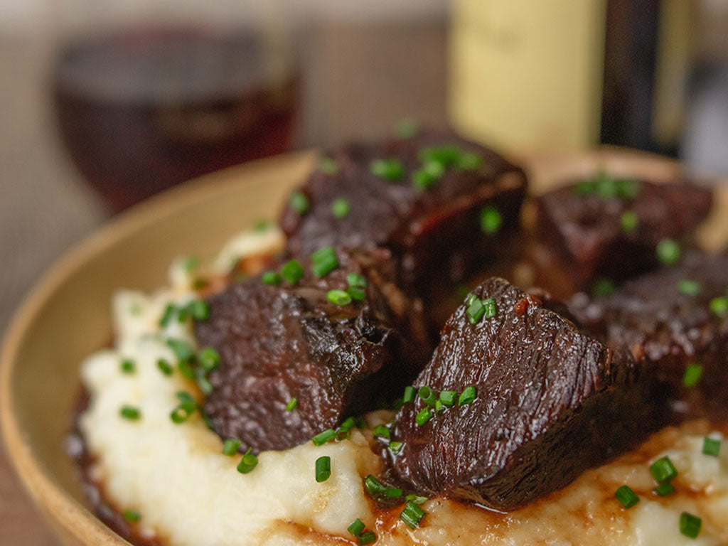 Close-up view of Braised Beef on a plate prepared with a recipe including Cherry Zinfandel Jam, vegetables, and seasoning.