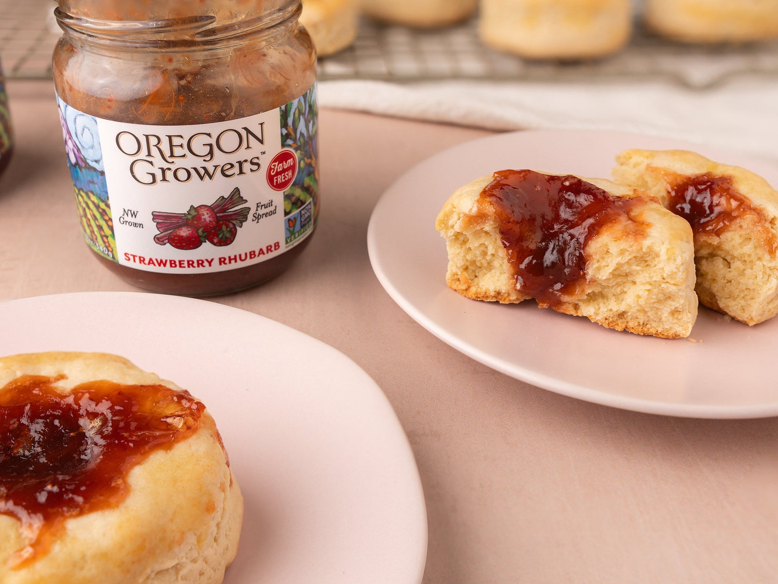 Closeup of Strawberry Rhubarb Jammer Biscuits on serving plates with a opened jar of Oregon Growers Strawberry Rhubarb Jam.