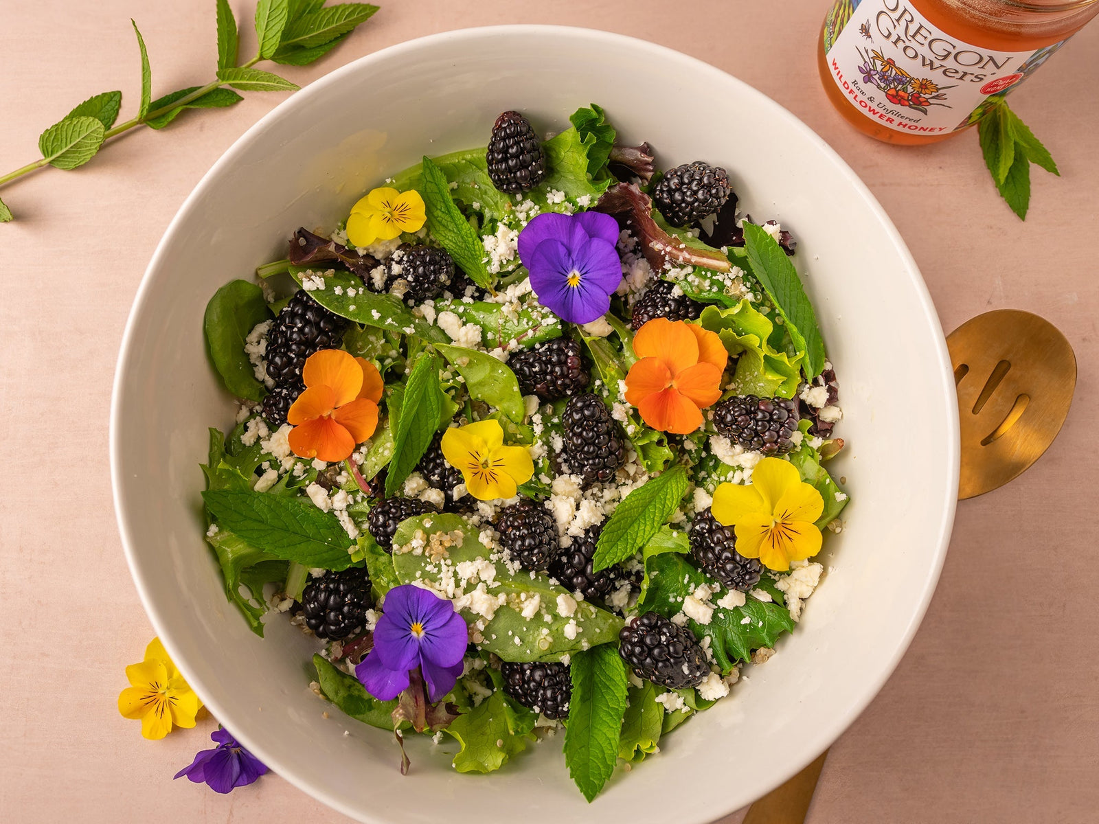 Top view of a bowl containing a Summer Salad With Honey Dressing, and Oregon Growers Recipe, accompanied by a jar of Oregon Growers Wildflower Honey.