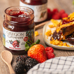Close-up of our Triple Berry Jam on a table with fresh fruit.