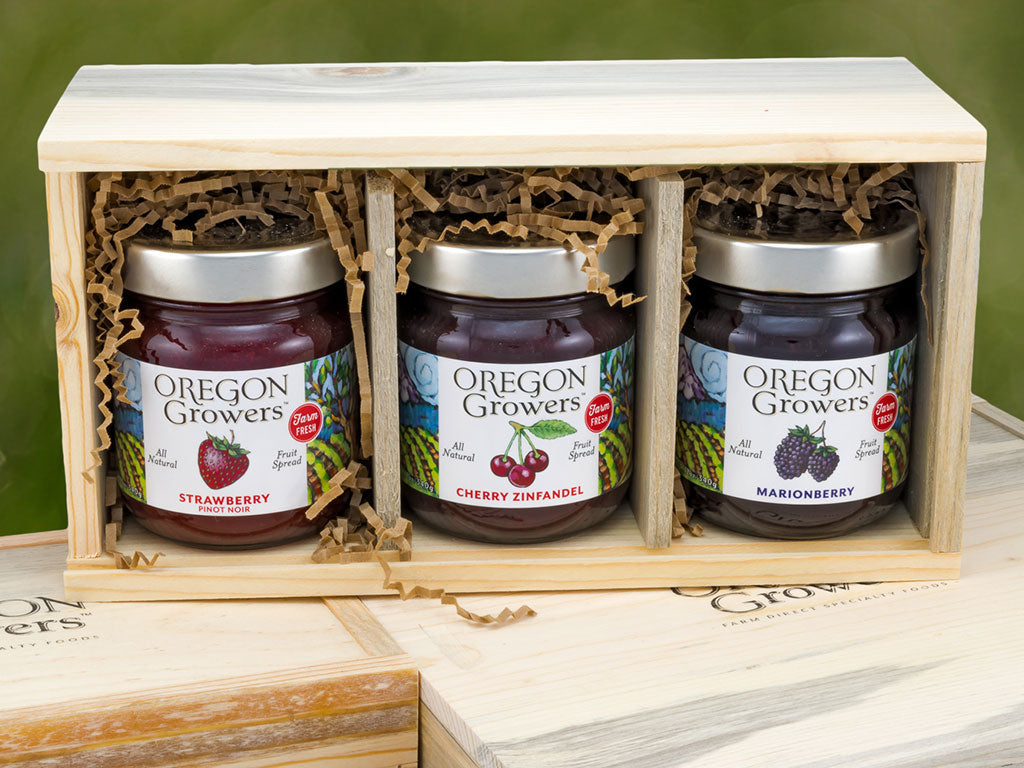 A gift box from Oregon Growers contains three jars of fruit spreads: Strawberry Pinot Noir, Cherry Zinfandel, and Marionberry.