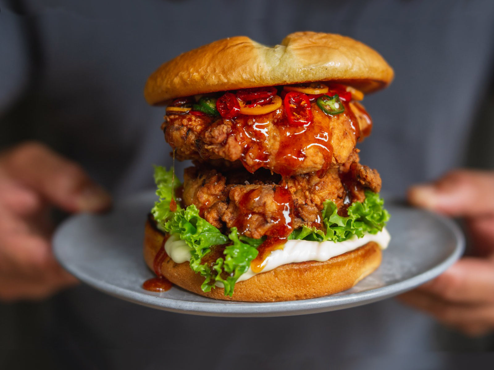 A large buttermilk fried chicken sandwich served with sliced chilies, garnish, and drizzled with Oregon Growers' Honey.