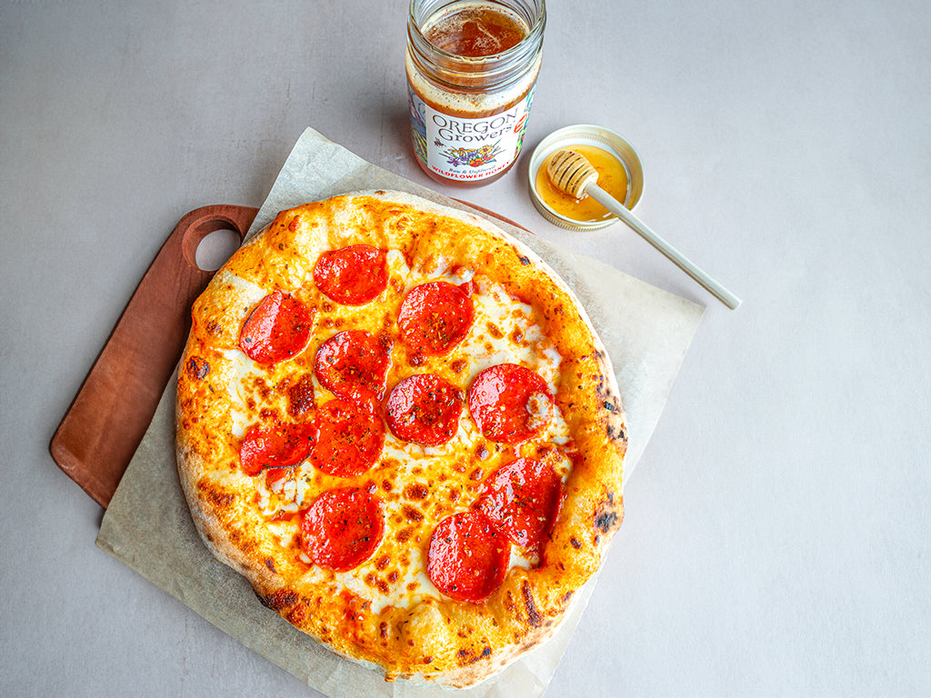 Top View of a Pizza on a Table Dripping with The DIY Hot Honey Recipe by Oregon Growers.