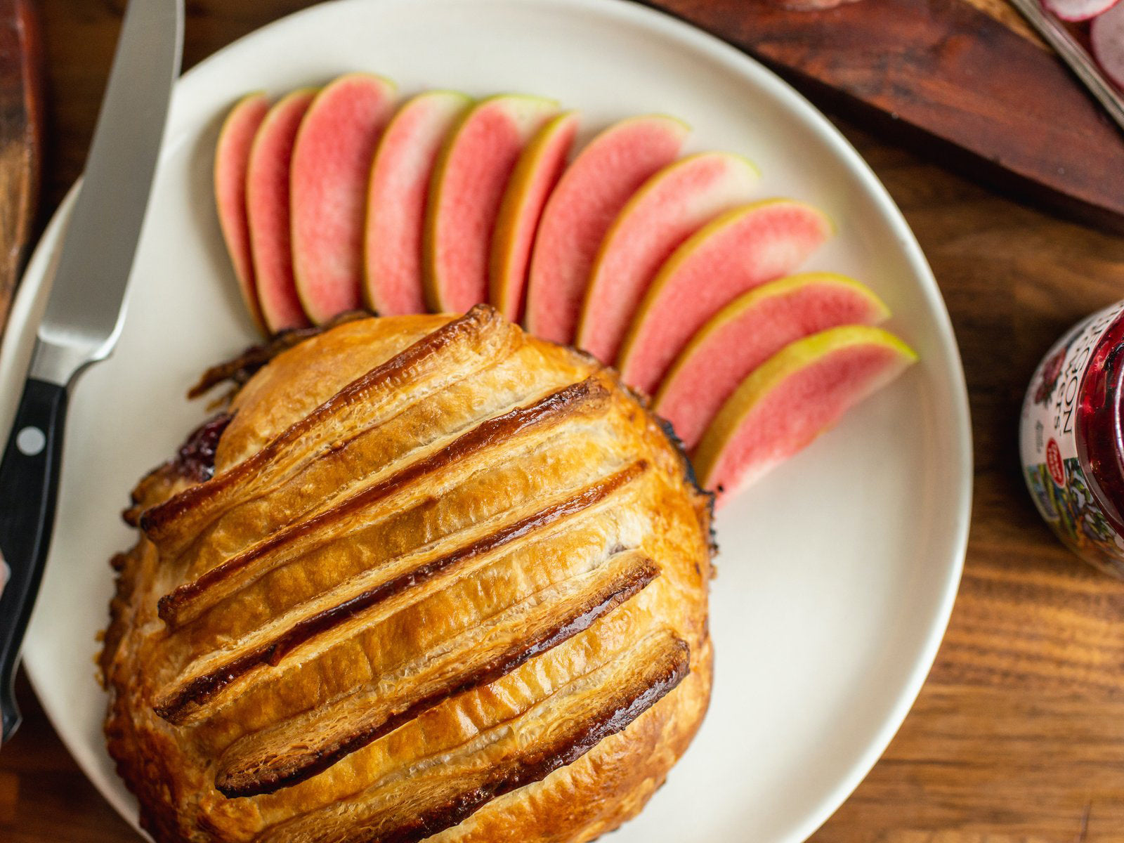 The top view of a serving plate with our recipe—the Jammy Puff Pastry Baked Brie. Served with slices of apples.