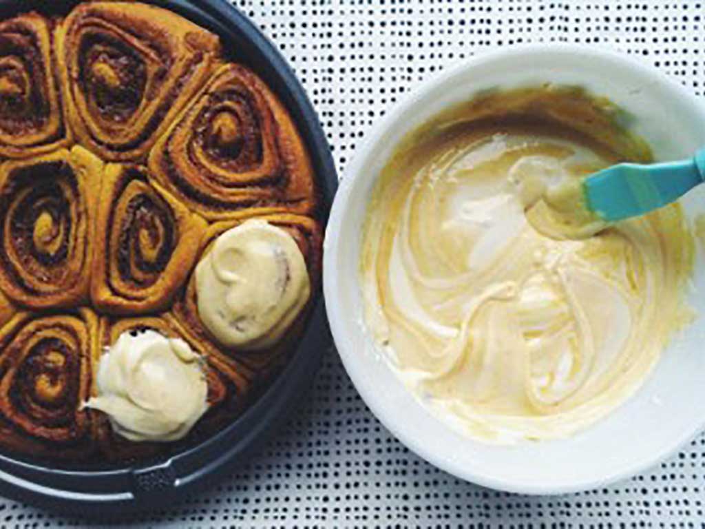 Top view of Cinnamon rolls with a bowl of cream cheese frosting made from from Oregon Growers Pumpkin Butter.