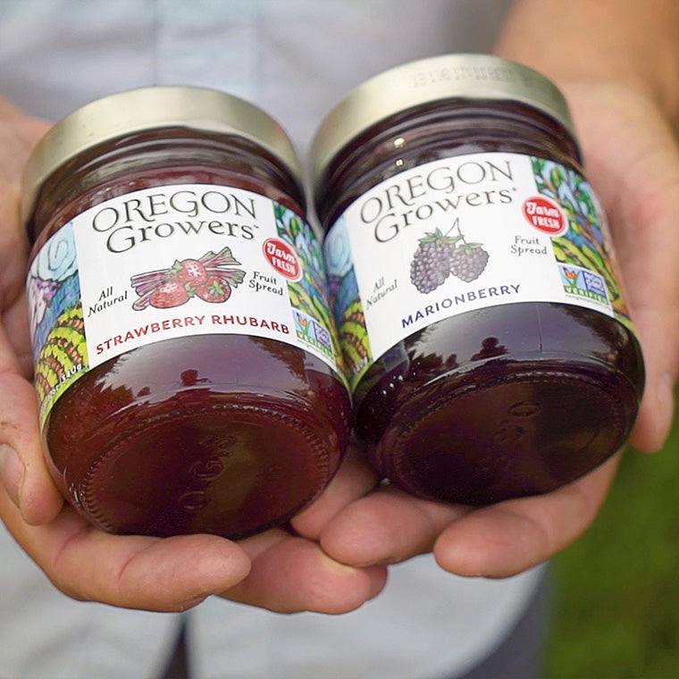 A close-up of hands holding our Strawberry Rhubarb and Marionberry jams as they just finished bottling and ready for distribution. 
