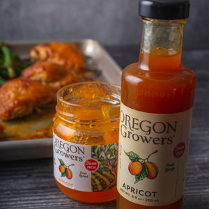  Our 8 oz. Apricot Fruit Syrup bottle on a table in front of a baking tin filled with glazed chicken.