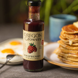 Our 8 oz Rasberry Fruit Syrup jar in front of a breakfast meal with pancakes and eggs.
