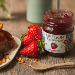 Close-up of 12 oz Strawberry Pinot Noir Jam next to fresh strawberries and a spoon.