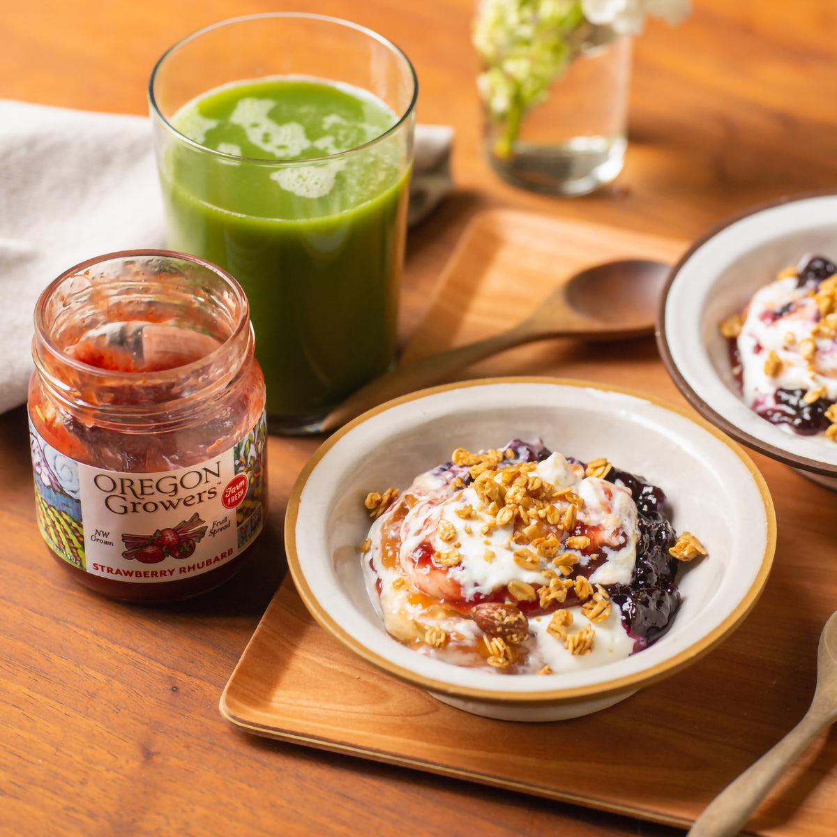 Healthy breakfast table with Strawberry Rhubarb Jam, bowl of yogurt, and a green smoothie.
